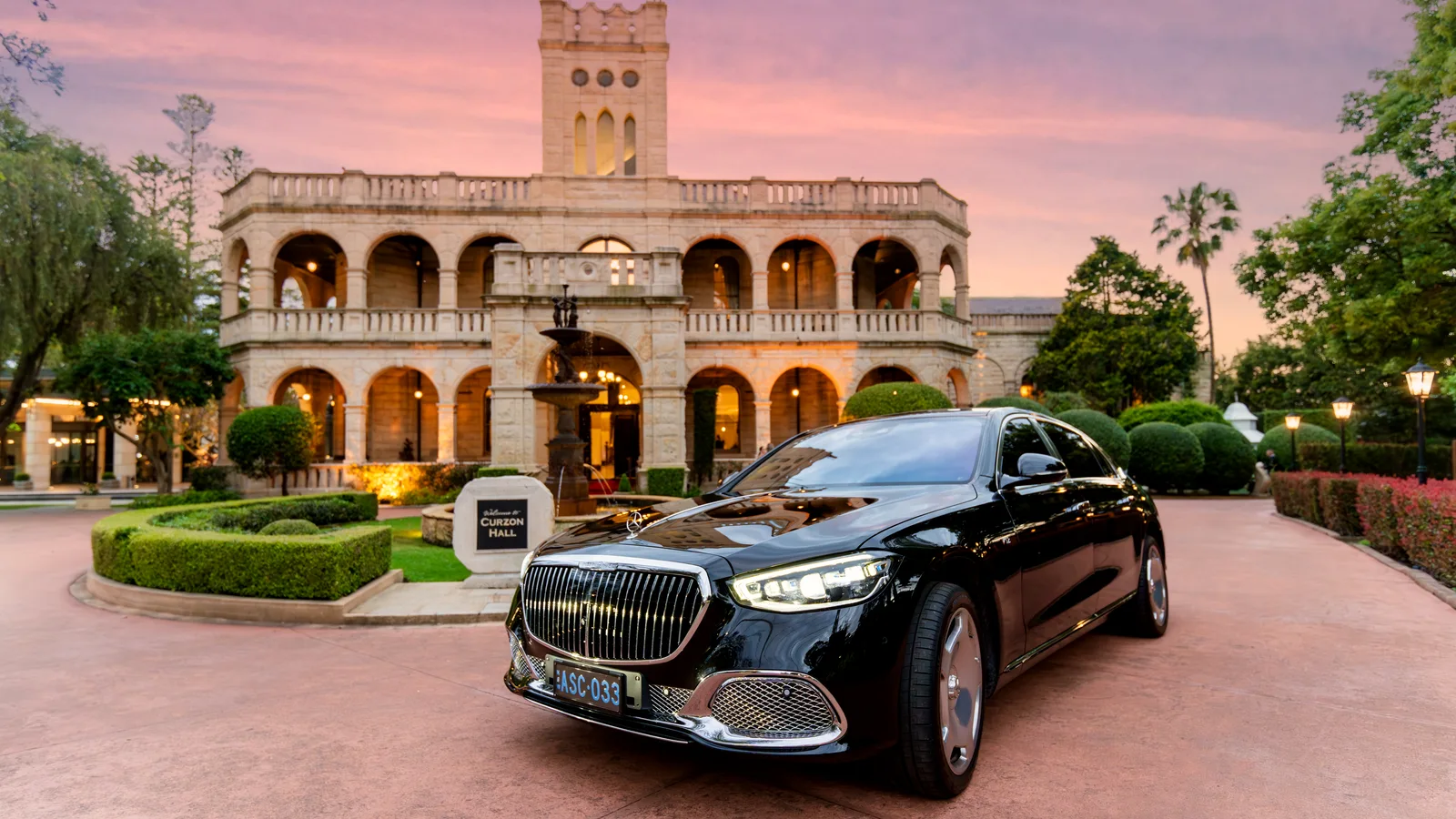 Black ASChauffeured Mercedes-Maybach S 680 outside a heritage building at dusk
